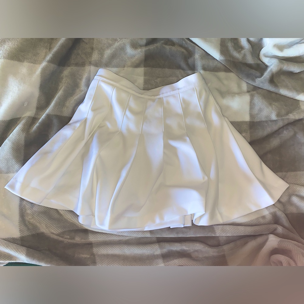 ! White pleated skirt. Spirit varsity, medium fit.